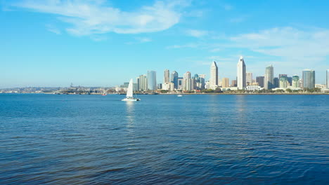 aerial view of a sailboat on san diego bay with the city skyline in the background