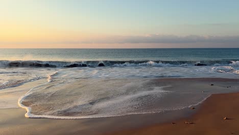 the cinematic scene of the seaside, where sea waves gently kiss the shore in the evening, reveals the vastness of the ocean surface