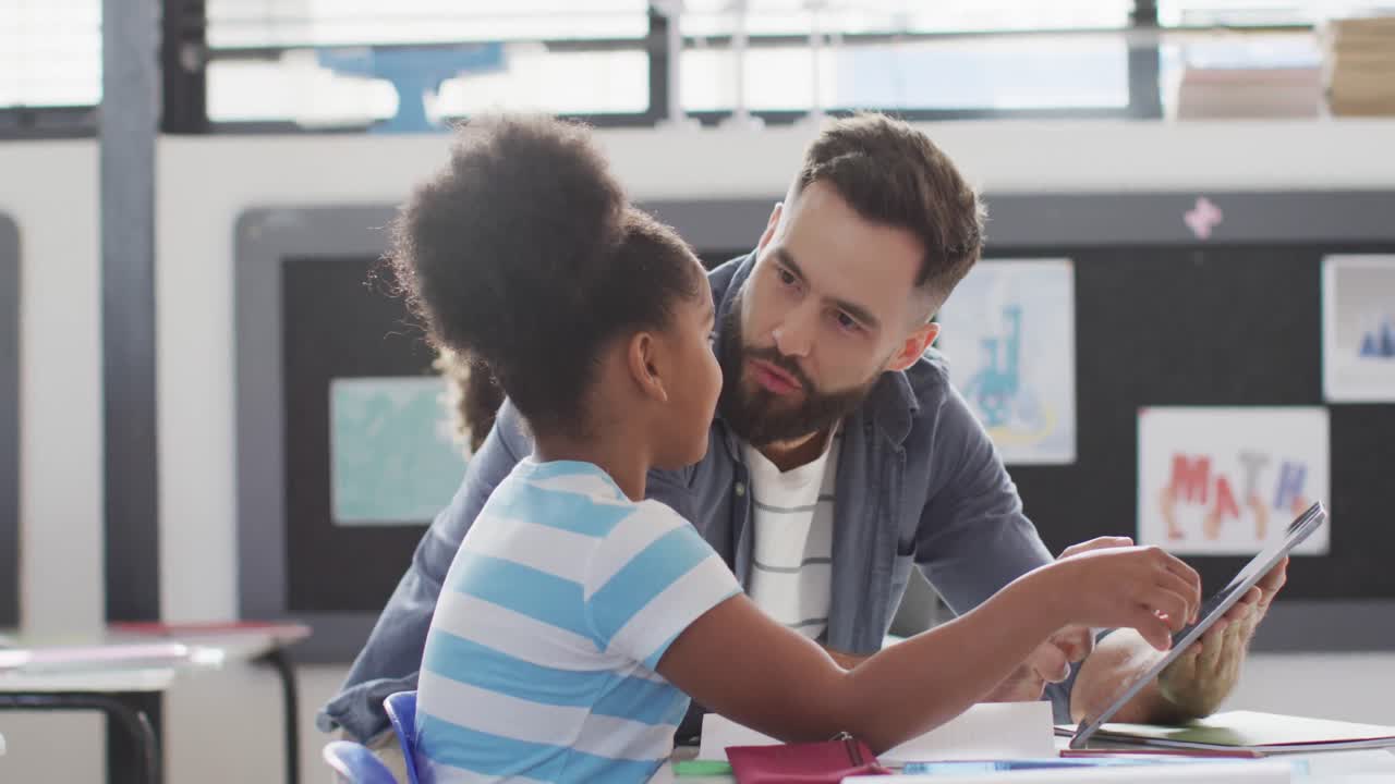 maestro masculino diverso y escolares felices usando tableta en el aula de la escuela