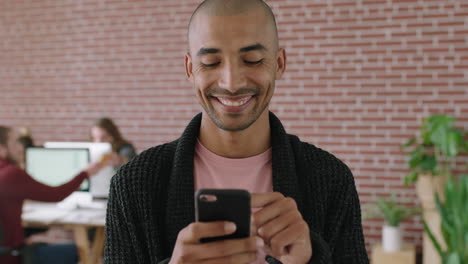 portrait-of-handsome-young-mixed-race-man-smiling-enjoying-texting-browsing-using-smartphone-social-media-app-in-office-workspace