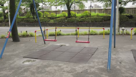 wide shot of empty red swings in a quiet park in chuo city, tokyo. overcast day