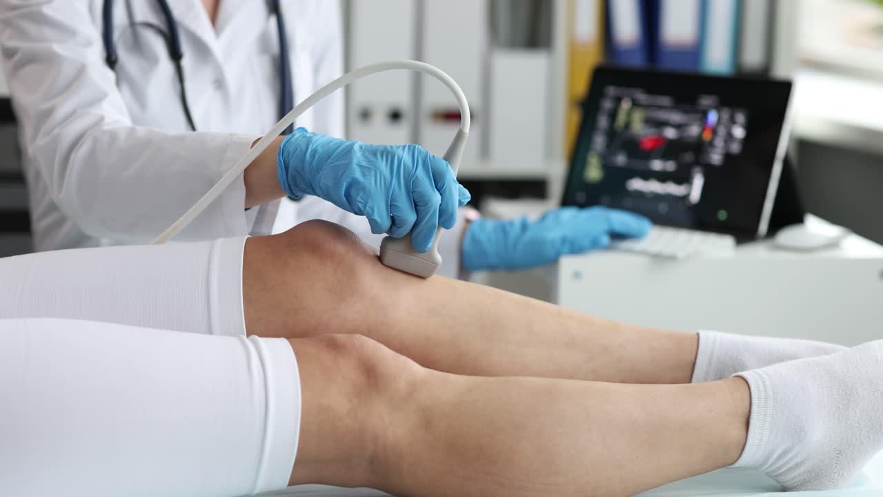 Doctor Performing Ultrasound Scan on Patient's Leg | Vídeo de stock Premium