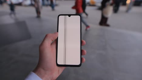 male hand holding smartphone mockup walking in a city swipe left touchscreen