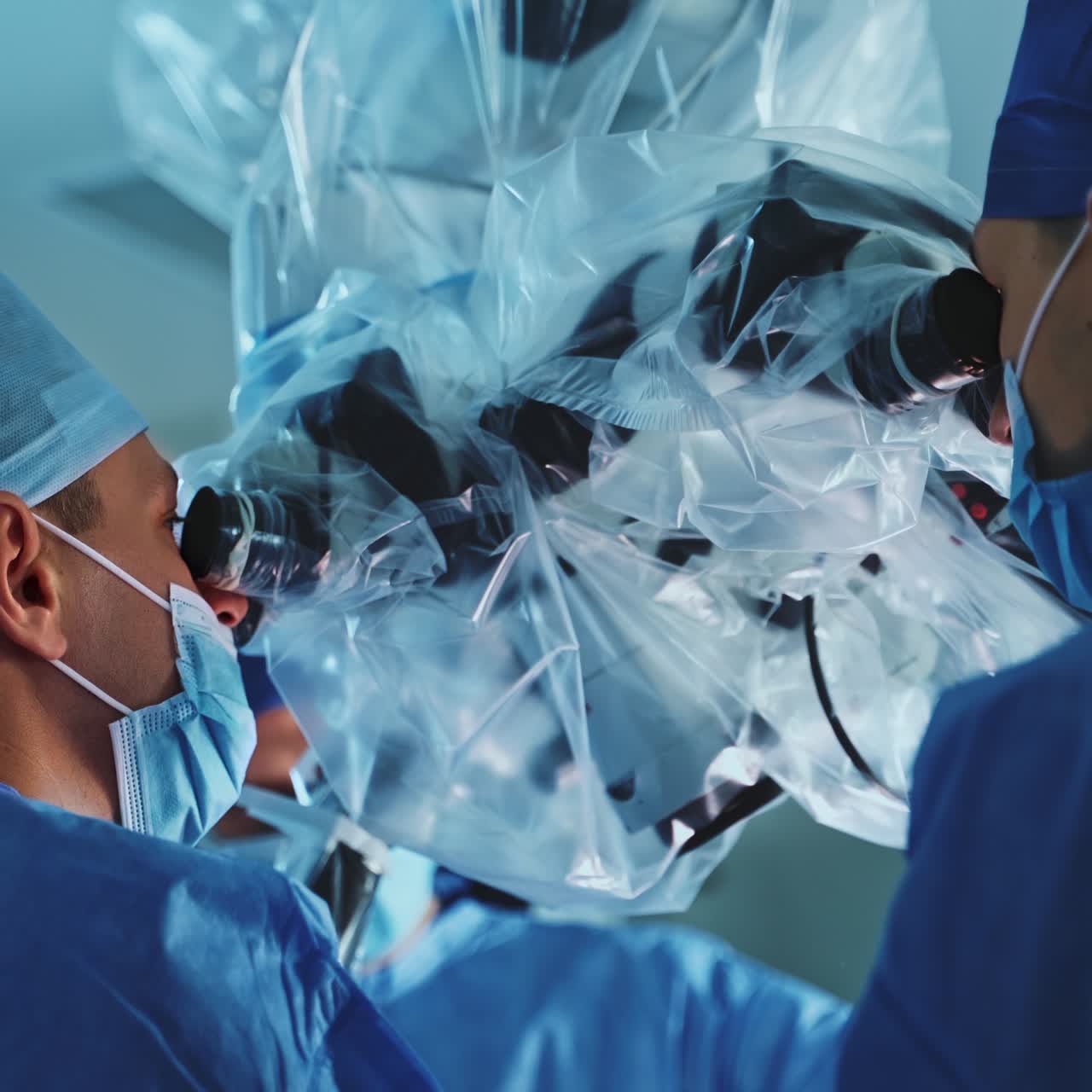 Male surgeons standing their backs to camera looking into the microscope. Medics using advanced equipment at surgery. Low angle view
