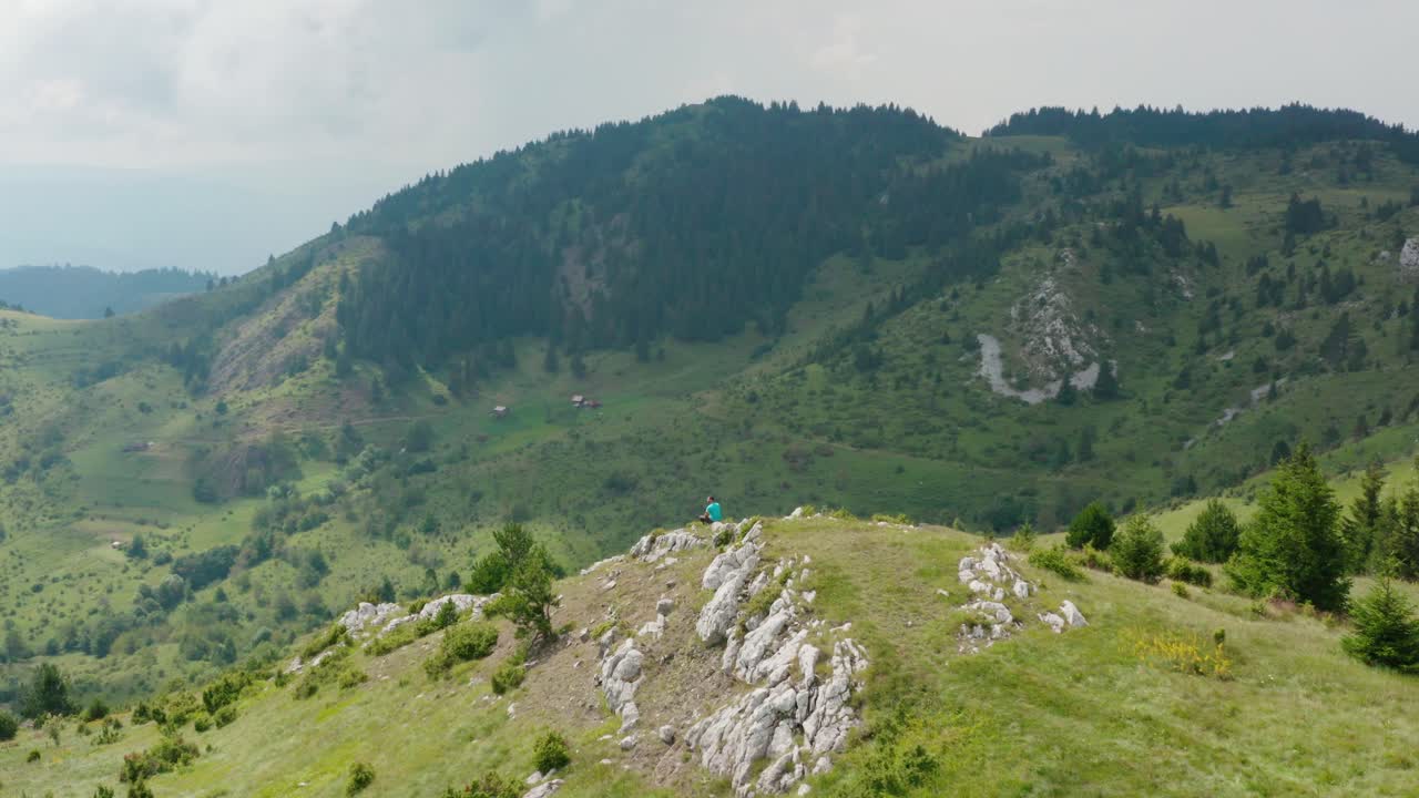 impresionante paisaje montañoso de jadovnik en serbia - excursionista masculino sentado en la cima del pico rocoso con vistas al paisaje montañoso - toma aérea de drones