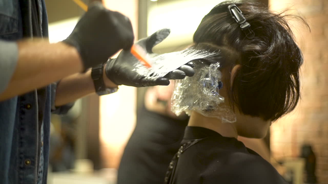 Parrucchiere professionista che esegue su una modella un trattamento per capelli.
