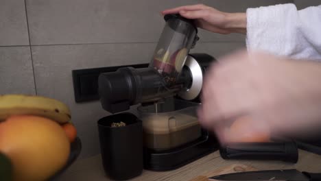 woman prepare apple or pear juice in the morning using juicer at kitchen