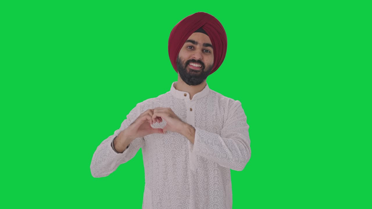hombre indio sikh feliz mostrando el signo del corazón pantalla verde