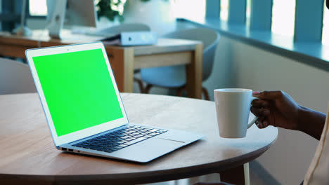 mujer ejecutiva usando una computadora portátil mientras toma café