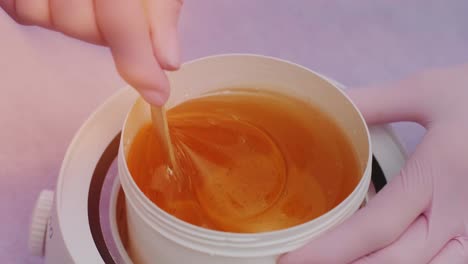 liquid sugar for skin epilation. close up shot. depilation and beauty concept - sugar paste or wax honey for hair removing with wooden waxing spatula sticks