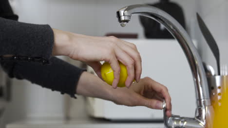 Plano-Medio-En-Cámara-Lenta-Como-Abrir-El-Grifo,-Lavar-Un-Limón-Con-Agua-Corriente