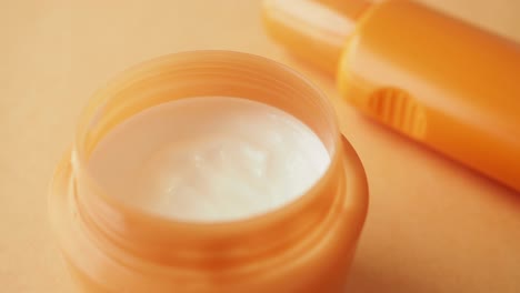 close-up of a jar of cream with a pink background