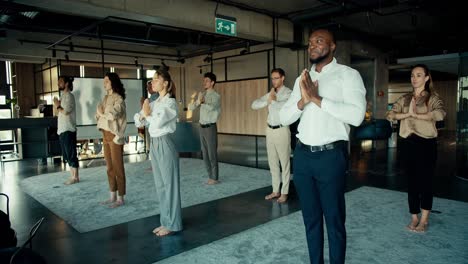 El-Equipo-De-La-Oficina-Se-Dedica-A-La-Meditación-Y-El-Yoga.-Los-Trabajadores-De-Oficina-Se-Paran-En-La-Alfombra-Y-Cruzan-Las-Manos-Frente-A-Ellos-En-La-Oficina