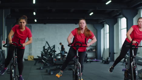 Group-of-girls-performs-aerobic-training-workout-cardio-routine-on-bike-simulators,-cycle-training