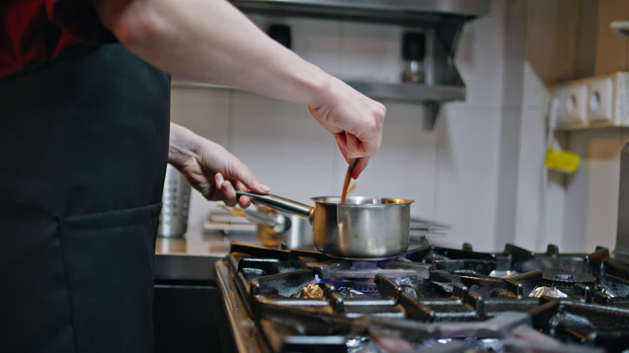 Professional cook preparing sauce at modern kitchen cooker closeup. Unknown man