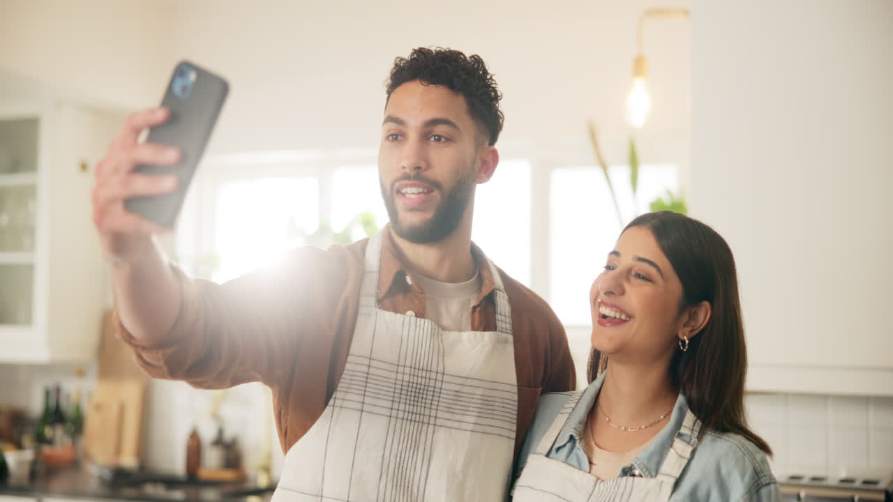 una pareja tomando selfies en la cocina.