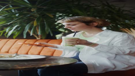 woman using phone and drinking smoothie in a cafe