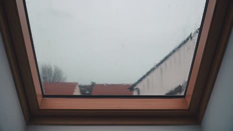 rain falling on a loft slanted bay window on an overcast day in england