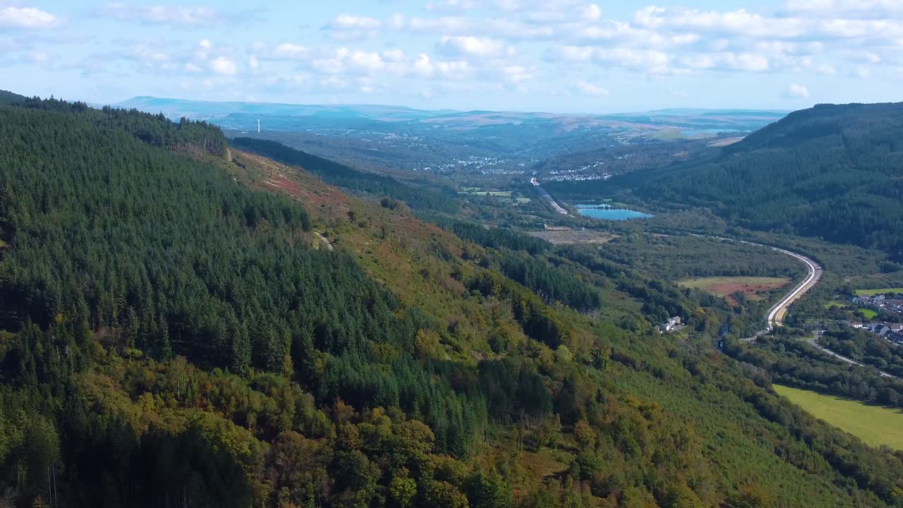 Aerial Towards Vast Open Landscape with Busy Dual Carriageway Heads of the Valleys Road with Cluster of Clouds and Dense Thick Woodland Forest on Mountain Side