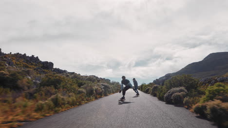 Jóvenes-Amigos-Practicando-Longboard-Juntos-Navegando-Por-Una-Carretera-Rural-Divirtiéndose-Montando-Patineta-Con-Casco-Protector-Adolescentes-Felices-Corriendo-Haciendo-Trucos