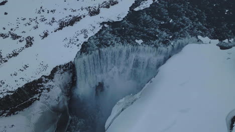 Luftaufnahme-Des-Isländischen-Wasserfalls-In-Kalter-Winterlandschaft,-Gletscherwasser-Und-Schnee,-Drohnenaufnahme