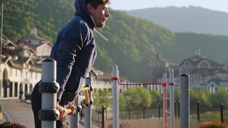 Man doing pull-ups in a park at sunrise