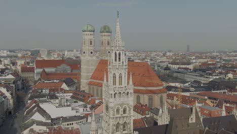 aerial view of munich new city hall aka rathaus, frauenkiche catholic cathedral at marienplatz, historic downtown square, descending drone shot