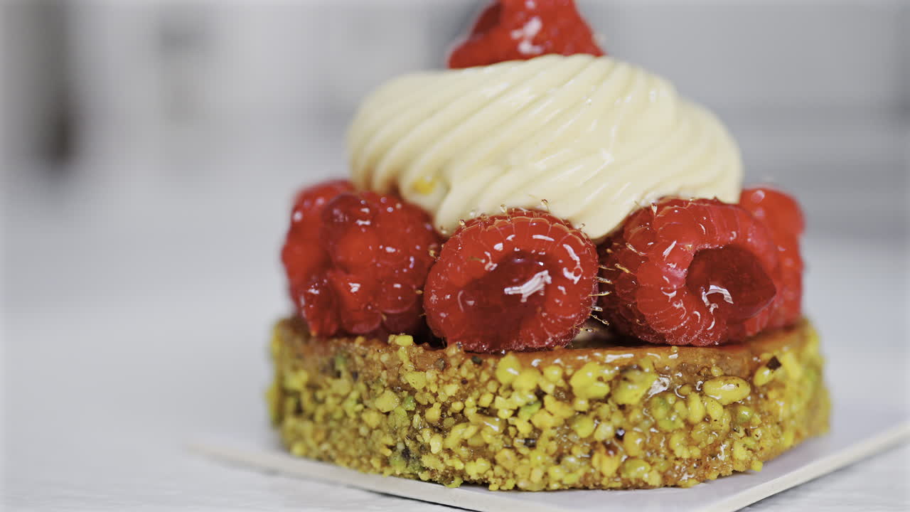 Close up of a pistachio raspberry tartlet on a white plate