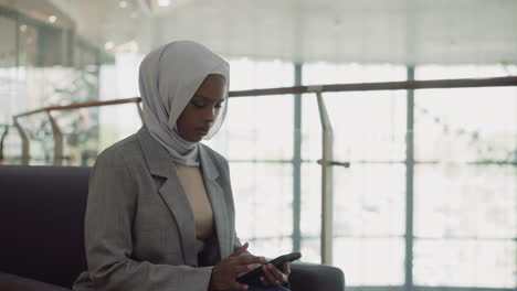 african-american business woman in hijab texts on phone