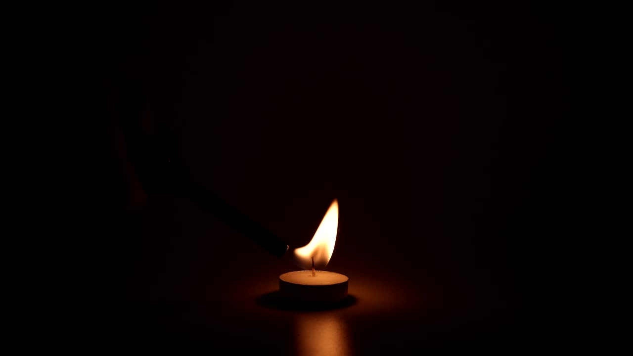 la llama de una vela arde y parpadea en la oscuridad.
