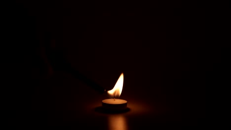 a candle's flame burns and flickers in the dark.