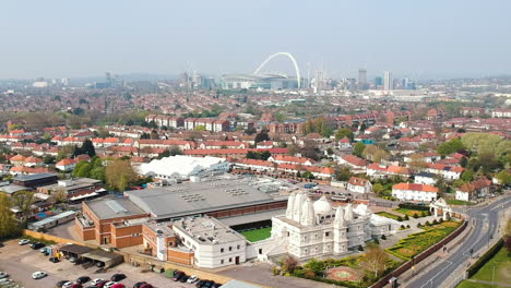 Ariel-view-of-BAPS-Shri-Swaminarayan-Mandir,-a-Hindu-Temple-in-Neasden,-north-west-London-with-Wembley-Stadium-in-background