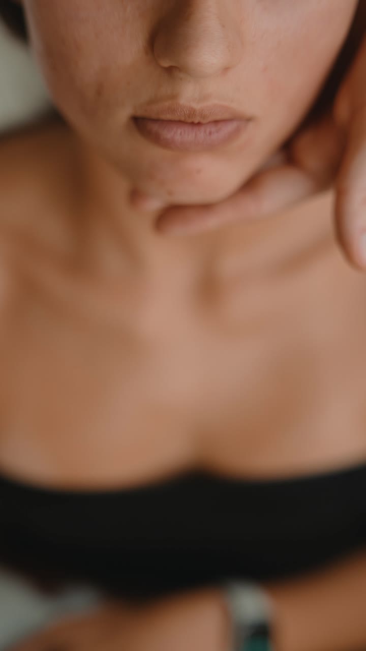 Primo piano di donna che usa lo strumento Gua Sha per massaggio facciale.