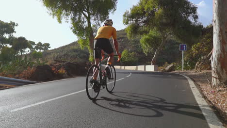 enjoying a tranquil morning, a man cycles on his road bike for outdoor exercise along a serene road. the slow-motion footage captures the essence of extreme sports