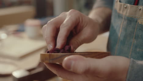 craftsman covering wooden drink coaster with oil