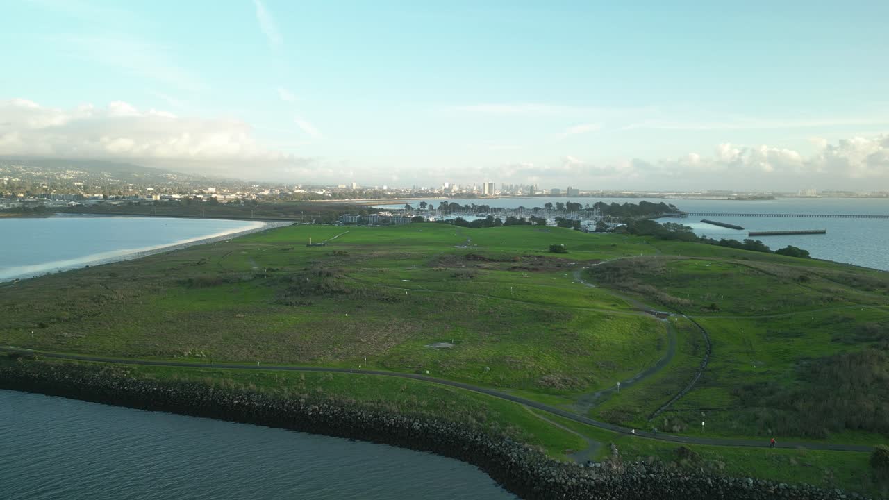 Breathtaking aerial view of Cesar Chavez Park in Berkeley, California, revealing vast grasslands, the Berkeley Marina, and the city skyline beneath a cloudy sky