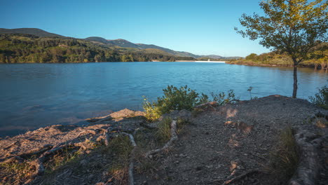 calm lake scene surrounded by mountains and trees on a clear sunny day