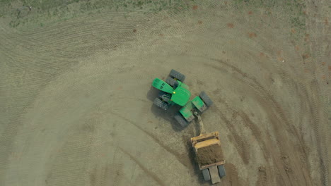 Antena-Arriba-Hacia-Abajo-Del-Tractor-Verde-Que-Transporta-Suelo-Con-Equipo-De-Movimiento-De-Suelo