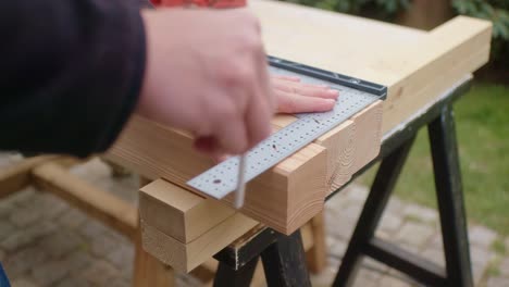 the man is measuring up and marking the wood