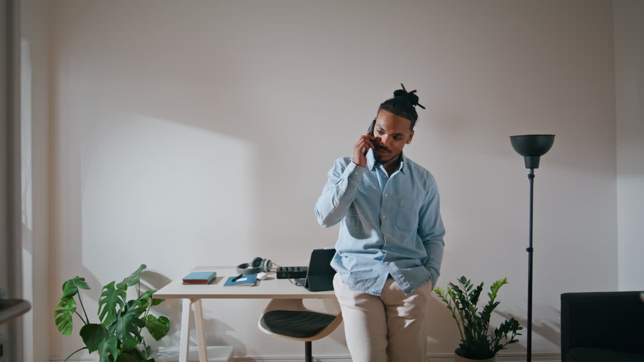 Fokuseret mand taler i mobiltelefon på hjemmekontoret. Dygtig professionel taler i mobiltelefon.