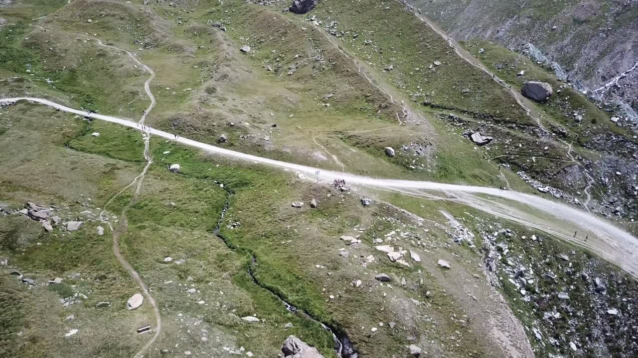 family on a mountain path, alps, Switzerland, drone aerial view. rocks, field