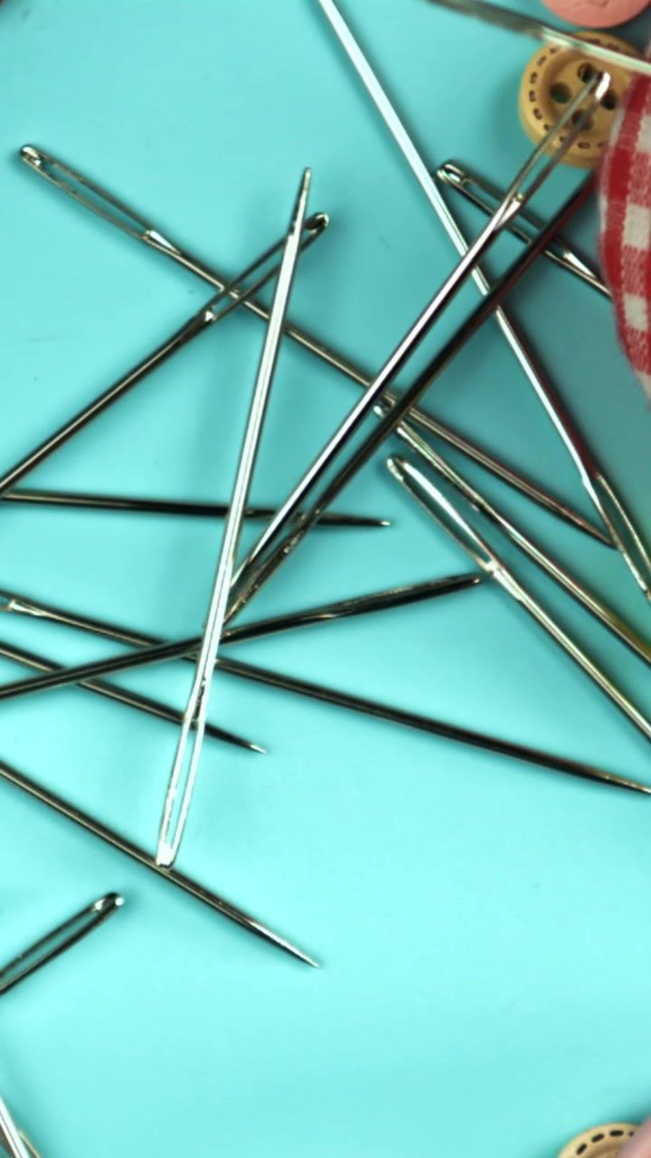 Silver Sewing Needles Falling on a Blue Background