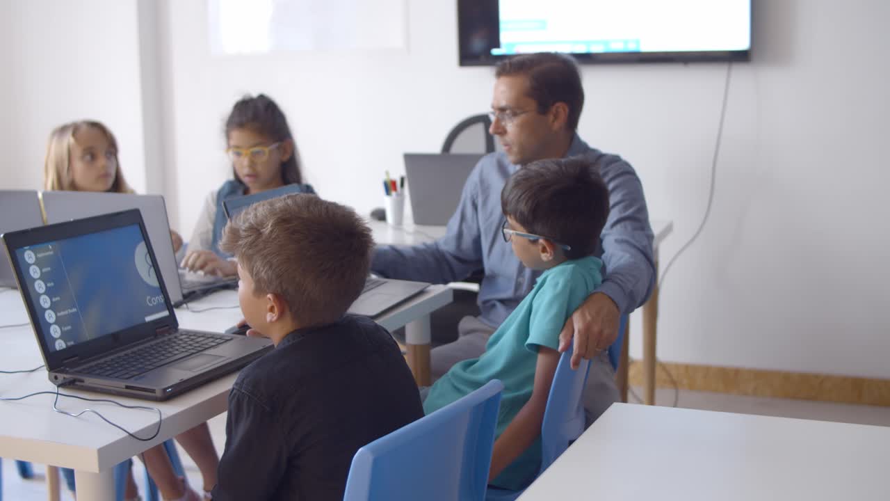 Computer science teacher helping pupils with task