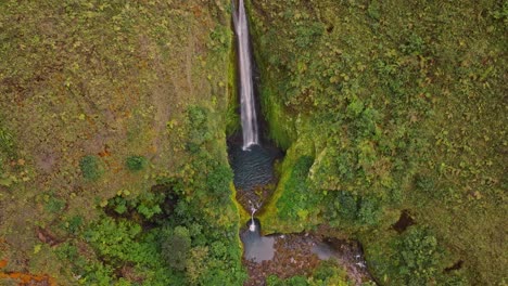 an breathtaking aerial view reveals the unique and beautiful vuelta al cañon waterfall, cascading majestically into a vibrant, untouched green canyon