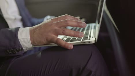 Cropped-shot-of-businessman-using-laptop-in-car