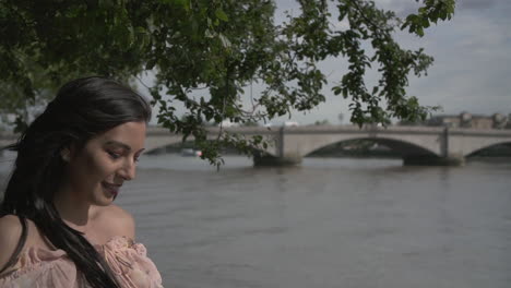 Attractive-Latina-woman-leaning-on-the-railing-of-a-bridge,-thinking-and-looking-around