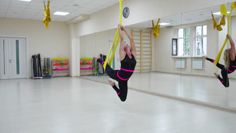 the concept of sports for a healthy lifestyle. the girl has been aerology of antigravity relaxes and swings on the canvas in a white room. rotation on the canvas around its axis