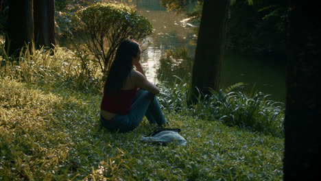 woman sitting by a lake in a park