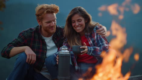 Closeup-camp-couple-cuddle-spend-time-in-mountains.-Two-lovers-hug-by-bonfire.