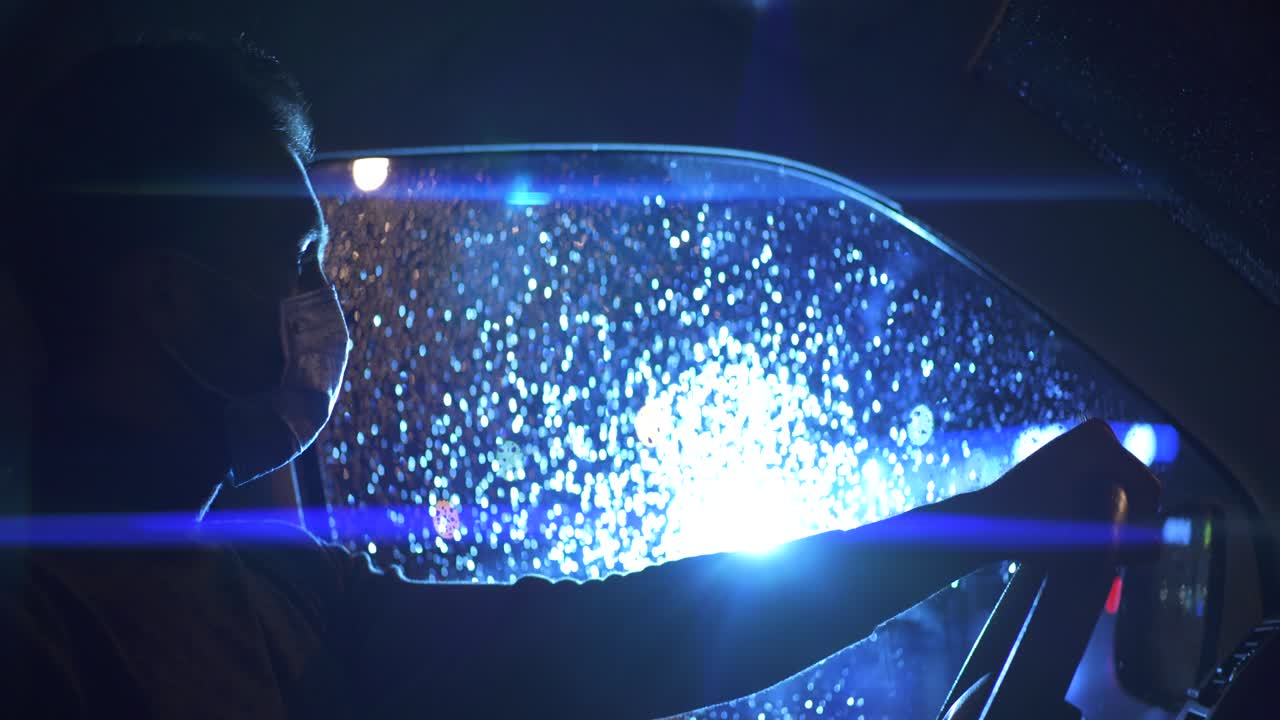 의료 마스크를 입은 젊은이가 차에 앉아 있습니다.